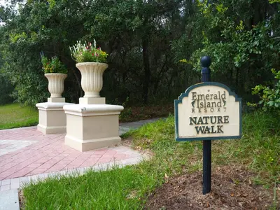 a sign in a yard with two vases on a sidewalk at Gated Emerald island resort townhome, Overlook Pool, 3 miles to Disney, rent by owner in Kissimmee