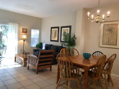 a dining room and living room with a table and chairs at Gated Emerald island resort townhome, Overlook Pool, 3 miles to Disney, rent by owner in Kissimmee