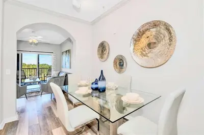 a dining room with a glass table and white chairs at Stunning 3BR Near Disney - Pool and Hot Tub! in Orlando