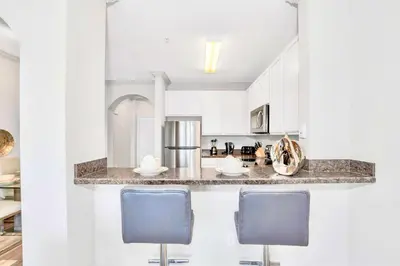 a kitchen with white cabinets and blue chairs at Stunning 3BR Near Disney - Pool and Hot Tub! in Orlando