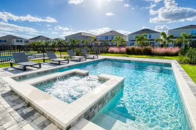 a swimming pool with chairs in a yard at Elegant Home Near Disney With Private Pool, Foosball Table, Themed Rooms And Waterpark & Resort Access At Encore Resorts Reunion - 365Sf in Kissimmee