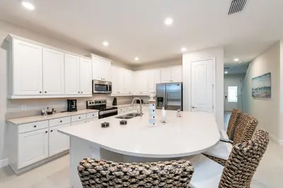 a kitchen with white cabinets and a large white island at Spacious Home With Game Room, Private Pool And Waterpark & Resort Access Near Disney At Encore Resorts Reunion - 241Sf in Kissimmee