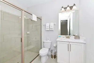 a white bathroom with a toilet and a shower at Modern Home Near Disney With Private Pool, Media, Game & Themed Rooms With Waterpark & Resort Access At Encore Resorts Reunion - 384Sf in Kissimmee