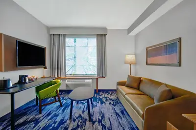 a hotel room with a couch and a desk and a television at Fairfield by Marriott Inn & Suites Orlando at FLAMINGO CROSSINGS® Town Center in Orlando