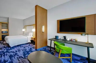 a hotel room with a bed and a desk with a tv at Fairfield by Marriott Inn & Suites Orlando at FLAMINGO CROSSINGS® Town Center in Orlando