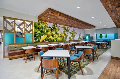 a restaurant with tables and chairs and a plant at Fairfield by Marriott Inn & Suites Orlando at FLAMINGO CROSSINGS® Town Center in Orlando