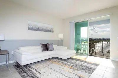 a living room with a white couch and a large window at Luxurious 2 Bd Close to Disney @ Storey Lake 204P in Kissimmee