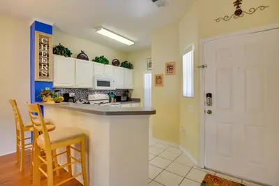 a kitchen with white cabinets and a counter with chairs at Near Disney and Epic Universe Home with Resort Perks in Kissimmee
