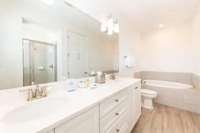 a white bathroom with a sink and a toilet at Sunset On Shaker Cottage With Private Pool Near Disney With Margaritaville Resort & Island H20 Access - 7960Sh in Orlando