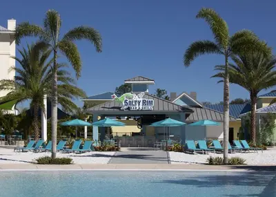 a resort with a swimming pool and chairs and palm trees at Comfy Cottage Near Disney With Margaritaville Resort & Island H2O Access - 8087Kd in Orlando