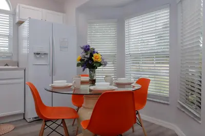 a kitchen with a table with chairs and a vase of flowers at Making Dreams 4BR Family Villa with Pool and Game Room Near Disney Parks in Kissimmee