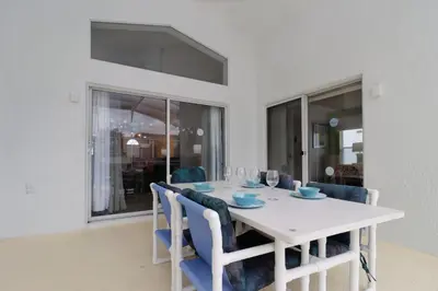 a white dining room with a white table and blue chairs at Making Dreams 4BR Family Villa with Pool and Game Room Near Disney Parks in Kissimmee