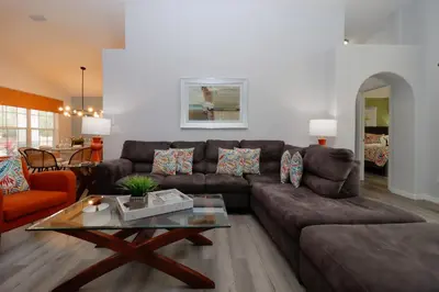 a living room with a brown couch and a table at Making Dreams 4BR Family Villa with Pool and Game Room Near Disney Parks in Kissimmee