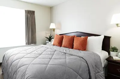 a bedroom with a large bed with orange pillows at InTown Suites Extended Stay Orlando FL – Presidents Dr in Orlando