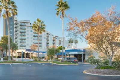 a parking lot with palm trees and a building at Modern Studio on I-Drive: parking + pool included in Orlando