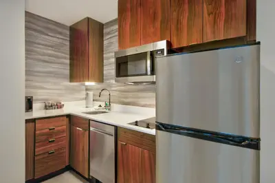 a kitchen with a stainless steel refrigerator and wooden cabinets at Residence Inn by Marriott Orlando at FLAMINGO CROSSINGS Town Center in Orlando