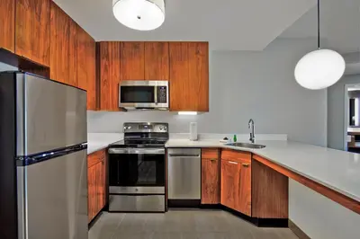 a kitchen with wooden cabinets and a stainless steel refrigerator at Residence Inn by Marriott Orlando at FLAMINGO CROSSINGS Town Center in Orlando