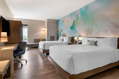 a hotel room with two beds and a painting on the wall at Cambria Hotel Orlando Airport in Orlando