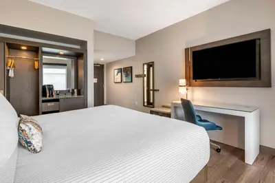 a hotel room with a bed and a desk and a tv at Cambria Hotel Orlando Airport in Orlando