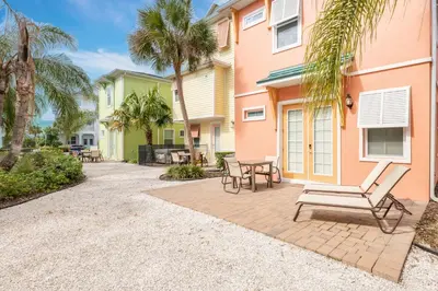 a patio with a table and chairs and palm trees at Vivid Cottage Near Disney With Margaritaville Resort & Island H2O Access - 8020Ff in Orlando