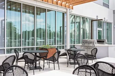 a patio with tables and chairs and windows at TownePlace Suites By Marriott Orlando Southwest Near Universal in Orlando