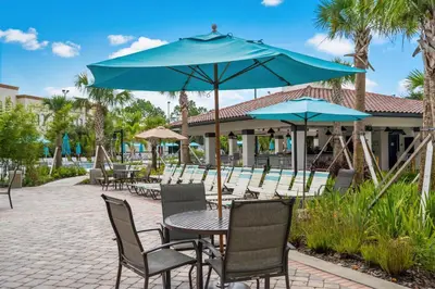 a patio with tables and chairs with blue umbrellas at Luxury 3BR resort Condo walking distance to Epic Universe, Convention center and Icon Park in Orlando
