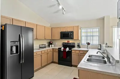 a kitchen with a black refrigerator and a sink at South Facing Pool Deck - Private Outlook - Game Room - Family Friendly - Nr Disney in Orlando