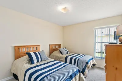 a bedroom with two beds with blue and white striped sheets at South Facing Pool Deck - Private Outlook - Game Room - Family Friendly - Nr Disney in Orlando