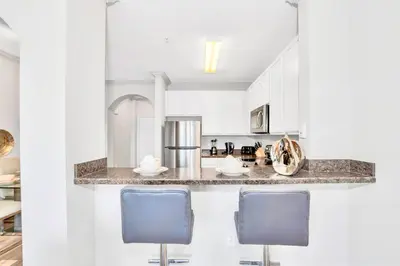 a kitchen with white cabinets and blue bar stools at Modern 3BR Near Disney - Pool in Orlando
