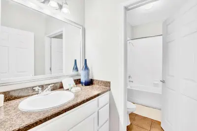 a bathroom with a sink and a toilet and a mirror at Luxury 3BR Near Disney - Pool and Hot Tub! in Orlando