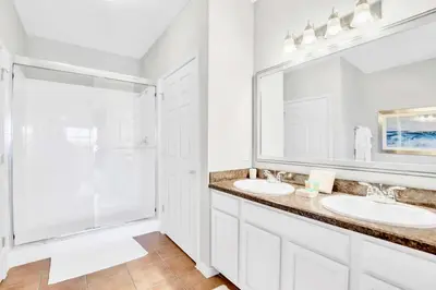 a white bathroom with two sinks and a shower at Refreshing 3BR Apartment Near Disney - Pool and Hot Tub! in Orlando