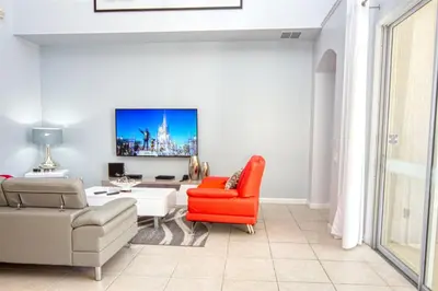 a living room with a red chair and a couch at 5 Bedroom 3 and half Bathroom Luxury Villa at Windsor Palms in Kissimmee