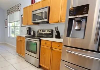a kitchen with stainless steel appliances and wooden cabinets at 5 Bedroom 3 and half Bathroom Luxury Villa at Windsor Palms in Kissimmee