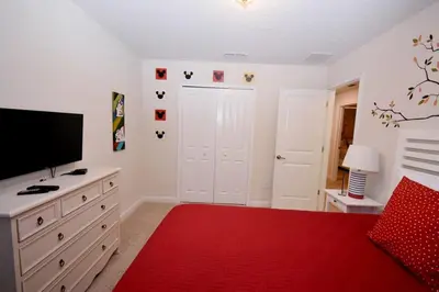 a bedroom with a bed with a television and a red rug at Luxury Pool Home, Spa, Grill- 1664St in Kissimmee