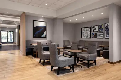 a waiting room with tables and chairs at Hyatt Place Orlando Airport in Orlando