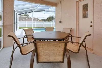 a table and chairs on a patio with a pool at Indian Ridge- 4 Bedroom Pool Home- 2405Ir in Orlando