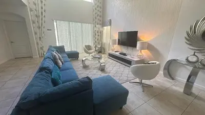 a living room with a blue couch and a tv at Pool Home With Privacy, Bbq, Mickey Room - 3500Pp in Kissimmee