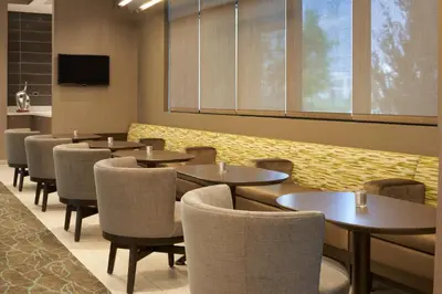 a dining room with tables and chairs and a tv at SpringHill Suites by Marriott Orlando Lake Nona in Orlando
