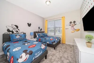 a bedroom with two beds with mickey mouse decorations on the walls at 2769RP VILLA 5 BED/5 BA (SANITIZED) in Kissimmee