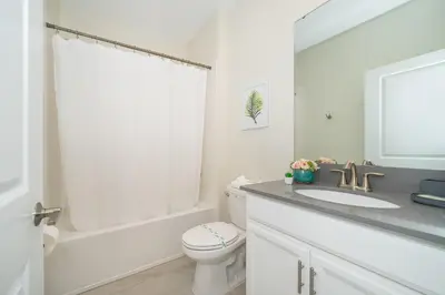 a white bathroom with a toilet and a sink at 2764SG VILLA 5 BED/5 BA (SANITIZED) in Kissimmee