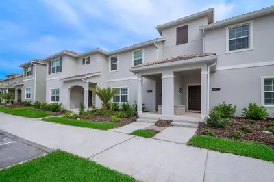 a large white house with a driveway at 4809AM TOWNHOUSE 4 BEDROOMS & 3 BATHROOMS + POOL in Kissimmee