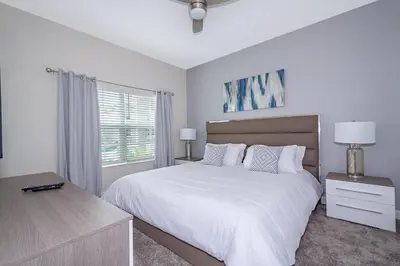 a white bedroom with a large bed and a window at 4809AM TOWNHOUSE 4 BEDROOMS & 3 BATHROOMS + POOL in Kissimmee