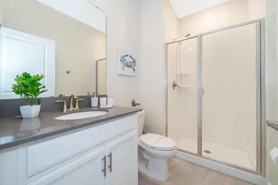a white bathroom with a toilet and a shower at 4313SL TOWNHOUSE 4 BEDROOMS & 3 BATHROOMS + POOL in Kissimmee