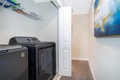 a laundry room with a washer and dryer and a painting at 4313SL TOWNHOUSE 4 BEDROOMS & 3 BATHROOMS + POOL in Kissimmee