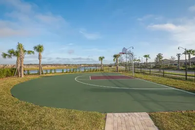 a tennis court with palm trees and a basketball hoop at 4313SL TOWNHOUSE 4 BEDROOMS & 3 BATHROOMS + POOL in Kissimmee