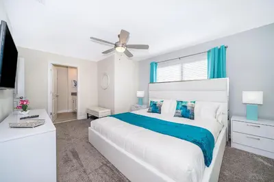 a white bedroom with a bed and a ceiling fan at 4393MO TOWNHOUSE 5 BEDROOMS & 4 BATHROOMS + POOL in Kissimmee