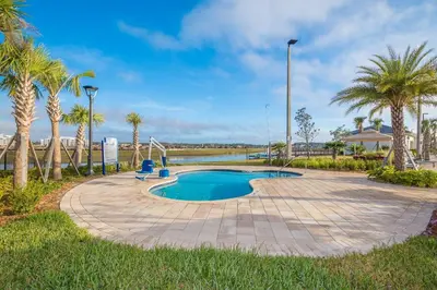 a swimming pool with palm trees in a park at 4393MO TOWNHOUSE 5 BEDROOMS & 4 BATHROOMS + POOL in Kissimmee