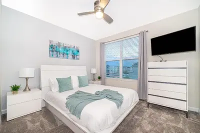 a white bedroom with a bed and a flat screen tv at 2811AS VILLA 5 BED/5 BA (SANITIZED) in Kissimmee