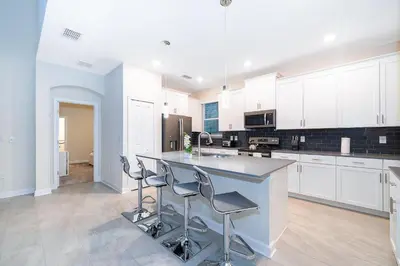 a kitchen with white cabinets and a island with bar stools at 2811AS VILLA 5 BED/5 BA (SANITIZED) in Kissimmee