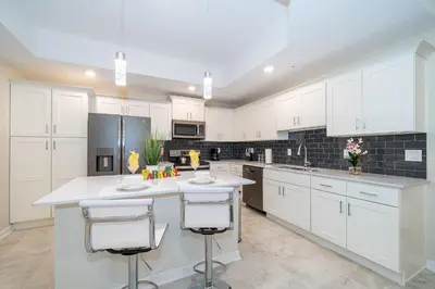 a kitchen with white cabinets and a large island with bar stools at 3150-308BR STOREY LAKE, CONDO 3/2 POOL VIEW in Kissimmee